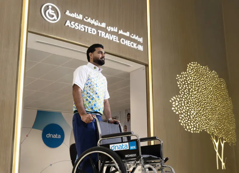 Dubai Havalimanı Assisted Travel check-in alanında tekerlekli sandalyeyle dnata çalışanı